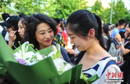 資料圖：山東濟(jì)南眾多考生手捧鮮花在家長(zhǎng)的簇?fù)硐職g快告別高考。中新社記者 張勇 攝