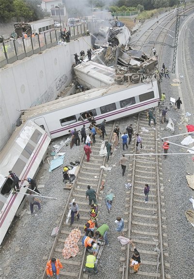 24日，救援人員在西班牙列車脫軌現(xiàn)場。一節(jié)車廂被強大的慣性拋上鐵道邊的高臺。
