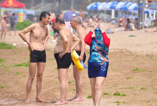 2013年7月3日，山東青島青島高溫來襲，“青島大媽”不懼滸苔，戴著“強(qiáng)盜面具”出現(xiàn)在海水浴場(chǎng)消暑降