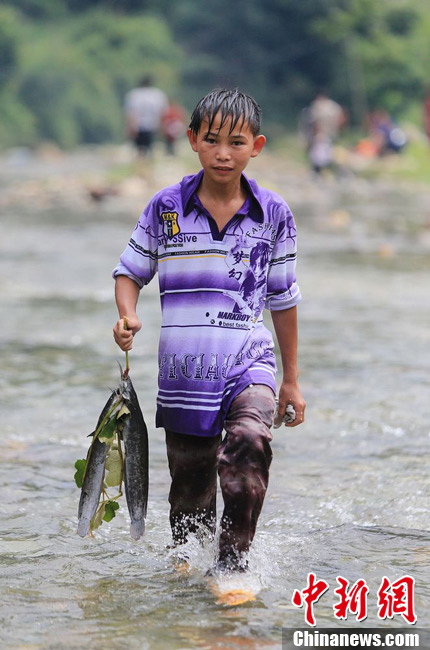 圖為7月9日，一名男孩在鬧魚節(jié)活動中抓到了兩條魚。譚凱興 攝