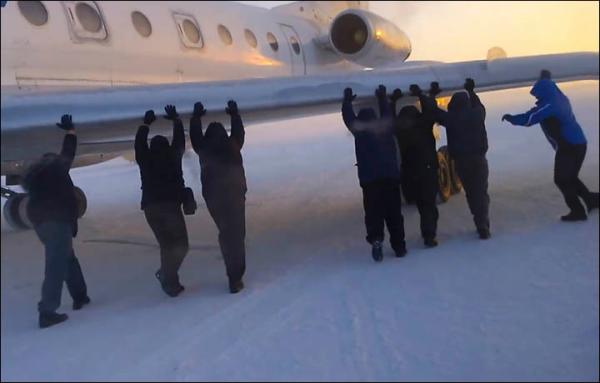 伊加爾市一架客機起飛前被凍在了跑道上。飛機上的乘客不得不下來推飛機。