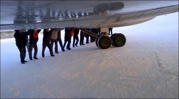 　伊加爾市一架客機起飛前被凍在了跑道上。飛機上的乘客不得不下來推飛機。