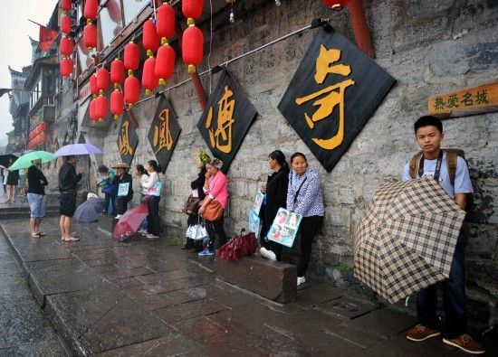 　4月29日上午11時20分，一些游客和古城當?shù)氐木用穸阍谝粋€酒吧的屋檐下避雨。這些當?shù)鼐用褚詾橛慰团恼罩\生，一場降雨讓他們的生意更加清淡。