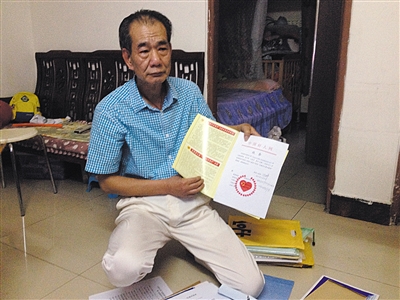 翻出一家網(wǎng)站贈(zèng)予的“中國好人”證書，區(qū)少坤單膝跪在地上，“你看，我是中國好人啊?！?范春旭 攝