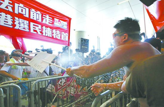 17日，在香港立法會(huì)外，一名反對(duì)政改的男子向支持派人群投擲標(biāo)牌。