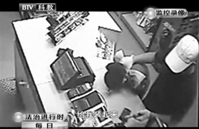 戴帽男子一手掐住加油站營業(yè)員，一手持發(fā)令槍指向另一營業(yè)員，要求“把錢給我裝起來”。