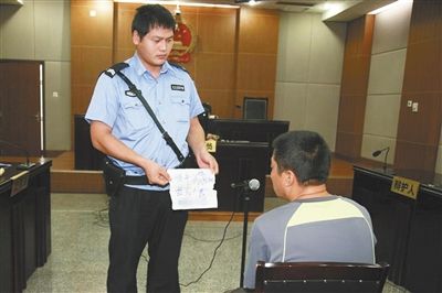 昨日庭審中，法警向趙某出示其扎完車胎后所留辱罵公司的紙條。通訊員 李秀文 攝