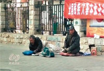 工人體育場(chǎng)北路，兩位乞討者路邊乞討，并輪流扮成“病人”（躺地者）。 央視截圖