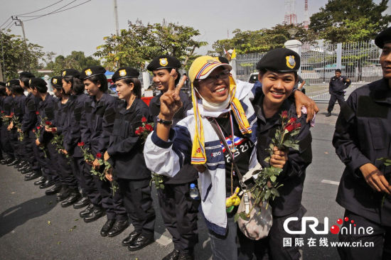 2013年12月03日,曼谷總理府與曼谷警署允許反政府示威民眾進入,雙方進入暫時“停戰(zhàn)”狀態(tài)迎接泰王生日。曼谷警察總署,女警們手持鮮花送給反政府示威民眾。圖片來源:Manish Swarup/東方IC