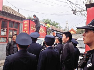 昨日下午,東城區(qū)工商、城管、公安等部門,對雍和宮附近的預(yù)測中心進(jìn)行清理整頓,站在車頂?shù)膬擅と苏鸪患摇邦A(yù)測中心”的招牌。因雍和宮、白云觀等文化景點(diǎn)外聚集大量算命先生,被媒體稱為“算命一條街”。本版攝影/新京報記者 李寧 攝