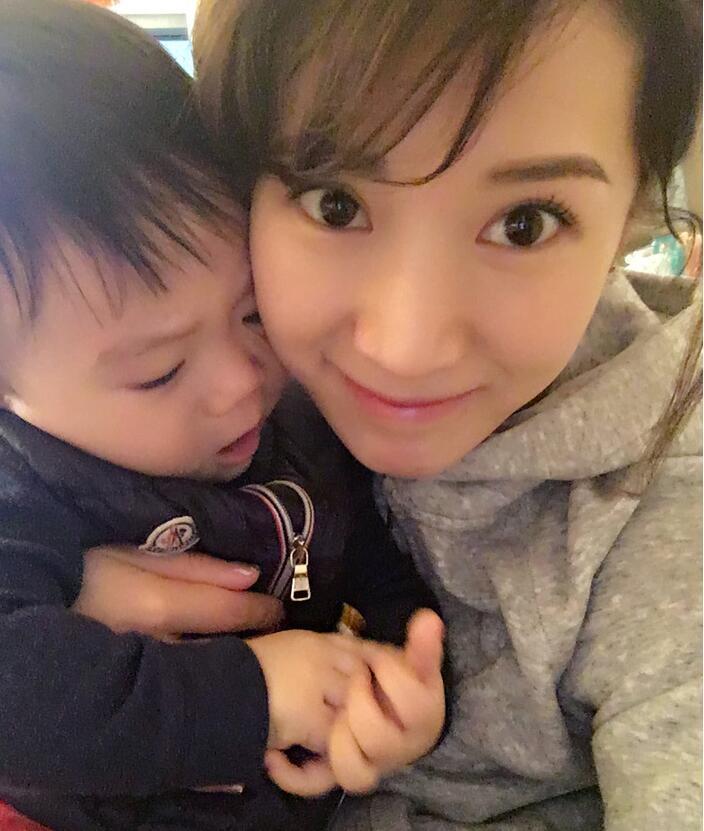 照片中李念狂吻兒子，小寶貝自顧自地玩著。