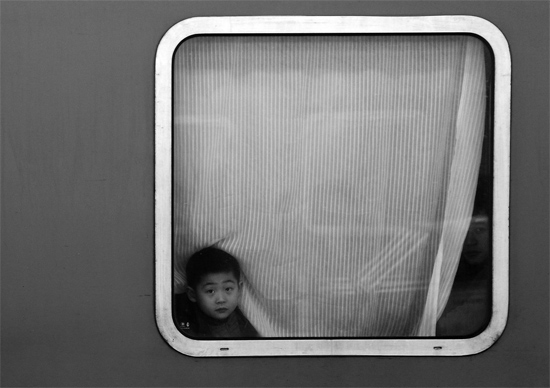 一個(gè)孩子把頭伸向窗外，他想再看送別的親人一眼