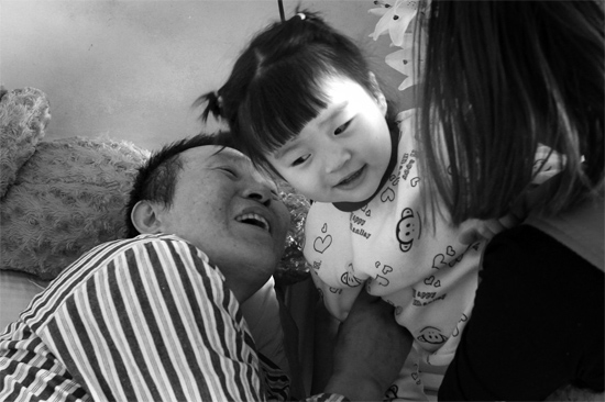 病床前李剛父女倆說著“悄悄話”，幸福的氣氛洋溢在病房中