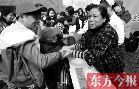 昨日，鄭大四附院的大樓前，“面人鄭”鄭玉芬（右）向前來捐款的殘疾人表示感謝
