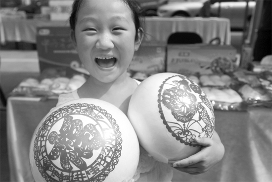 在2013河南食品安全宣傳周活動(dòng)現(xiàn)場，一個(gè)小女孩抱著參展的特色大饅頭樂開了花