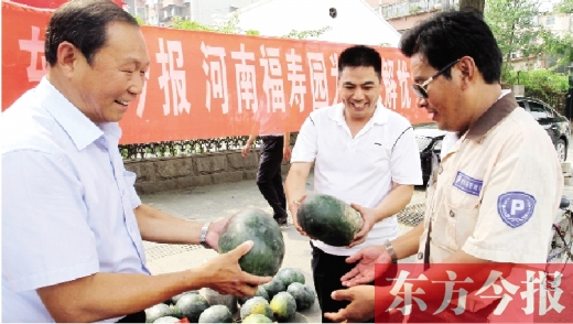 河南福壽園區(qū)域總經(jīng)理吳正宗（左一）、東方今報發(fā)行中心副總監(jiān)王路喜（中）在街頭給市民送瓜
