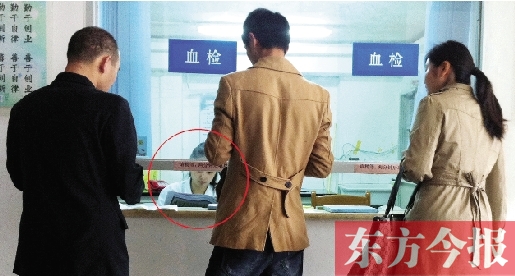 昨日，鄭州市二七區(qū)疾控中心辦證大廳，血檢窗口內(nèi)一名女工作人員，邊接受辦證者咨詢邊看報(bào)紙
