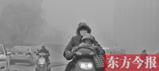 12月8日，鄭州市未來(lái)路上，一位市民帶著孩子在霧中騎行