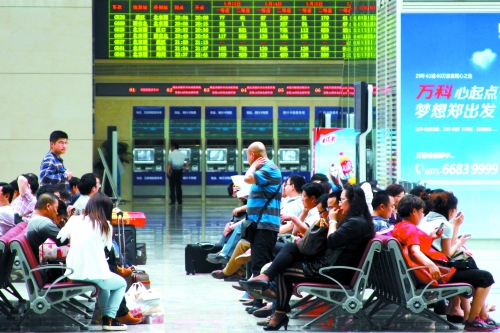 候車大廳溫度很高，一名乘客一手扇風、一手擦汗