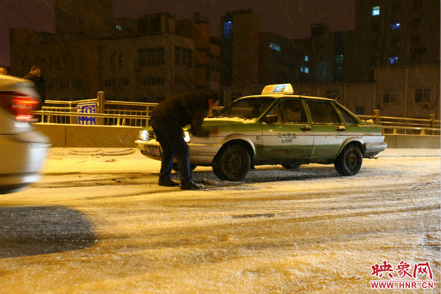 一位出租車(chē)司機(jī)在車(chē)輪前灑上雪，希望能增加輪胎的摩擦力。