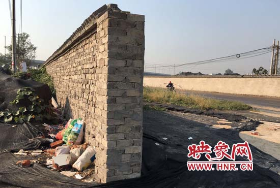 一墻之隔，一邊是道路，一邊是垃圾和荒草，市民質(zhì)疑其為遮羞墻。