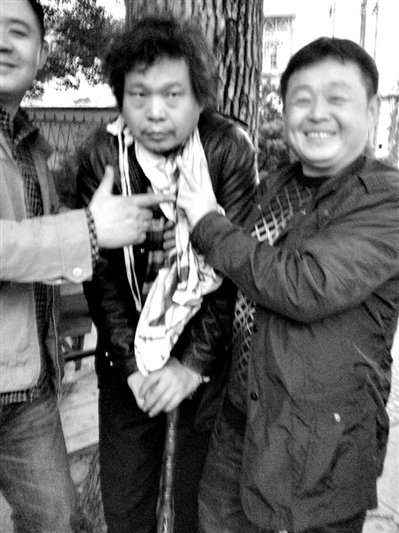 兩名接訪人員與患有癌癥的訪民段新德合影時(shí)，面帶笑容擺出勝利的手勢(shì)。
