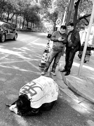 兩名接訪人員與患有癌癥的訪民段新德合影時(shí)，在拍照時(shí)查看手機(jī)。