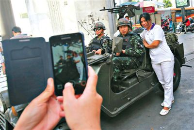 20日，泰國首都曼谷，一名婦女與執(zhí)行軍管任務的士兵合影。