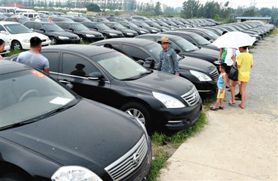昨日，市民在山東棗莊一家拍賣公司場地上查看待拍賣公車。當(dāng)日，棗莊市103輛公車公開拍賣。新華社記者
