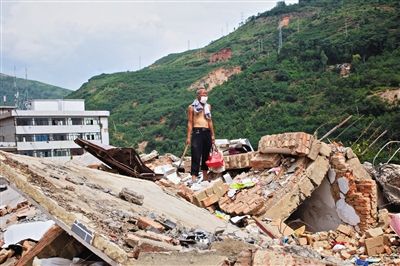 8月9日,龍頭山鎮(zhèn),一位老者在自家房屋廢墟上尋找家當(dāng)。