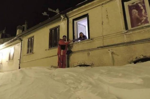 一個居民站在積雪上，可以與一名二樓鄰居在窗口握手。（來源：意大利氣象局）