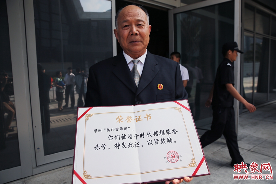 河南鄧州“編外雷鋒團”團長宋清梅向眾多記者展示中宣部授予的“時代楷模”榮譽證書。