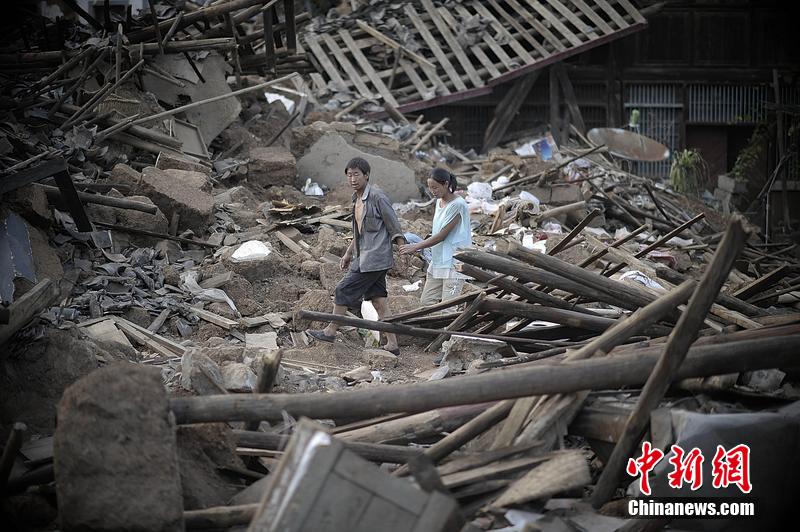 2014年8月5日，云南昭通龍頭山鎮(zhèn)老街，一對夫妻從居住房屋的廢墟中走過。