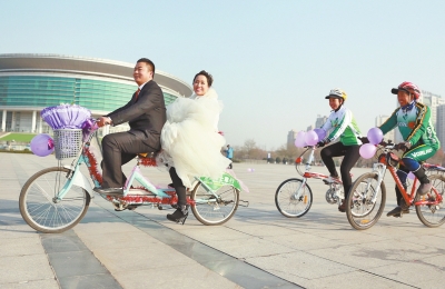 氣球和鮮花裝點(diǎn)的雙人自行車，新郎郝幸福載著美麗新娘回家。