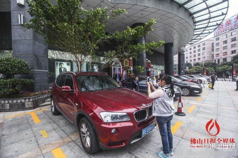 一輛停在停車位上的寶馬轎車，被墜落的樹枝砸中，樹枝徑直插入車內(nèi)，現(xiàn)場引發(fā)不少市民圍觀拍照。
