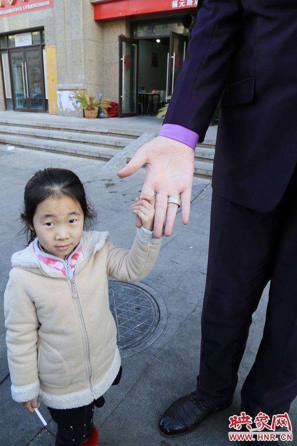巨人“張歡”牽著一名漂亮的小女孩，兩人的手大小對(duì)比非常明顯。