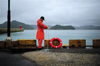 7月6日，韓國珍島，一名海岸警察在港口系救生圈。4月，客輪在珍島近海發(fā)生沉船事故后，仍有11人下落不明。