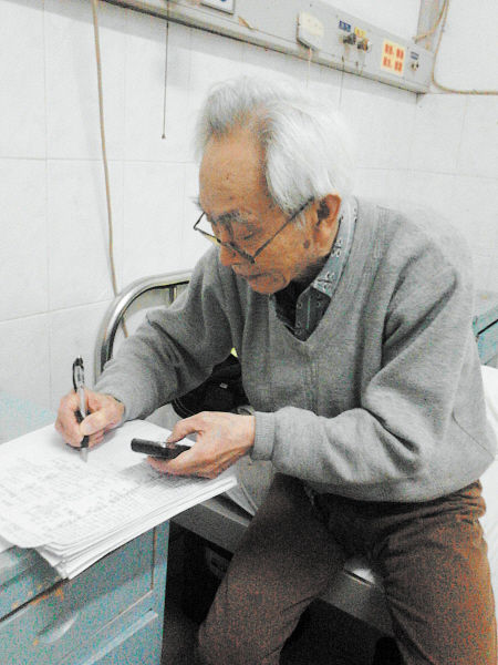 杜修源老人埋頭寫著特殊的“日記”。 李卓 攝