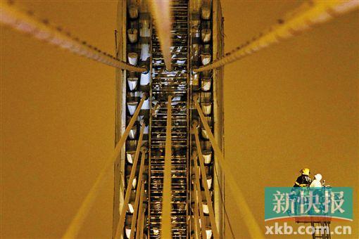 截至今日零時(shí)，男子仍未有下橋舉動(dòng)。圖為公安和消防人員乘消防云梯在高空上和男子交談。