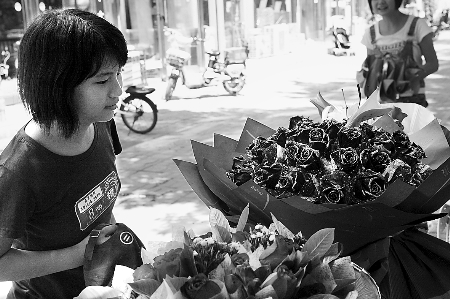 鄭州市農(nóng)業(yè)路一家花店擺放的玫瑰花吸引著一位過往女孩。