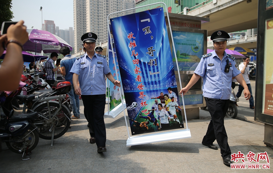 7月2日上午，鄭州市紫荊山地鐵站出入口，執(zhí)法人員抬著寫有勸導(dǎo)語的宣傳板，前往占道經(jīng)營攤位“圍觀執(zhí)法”